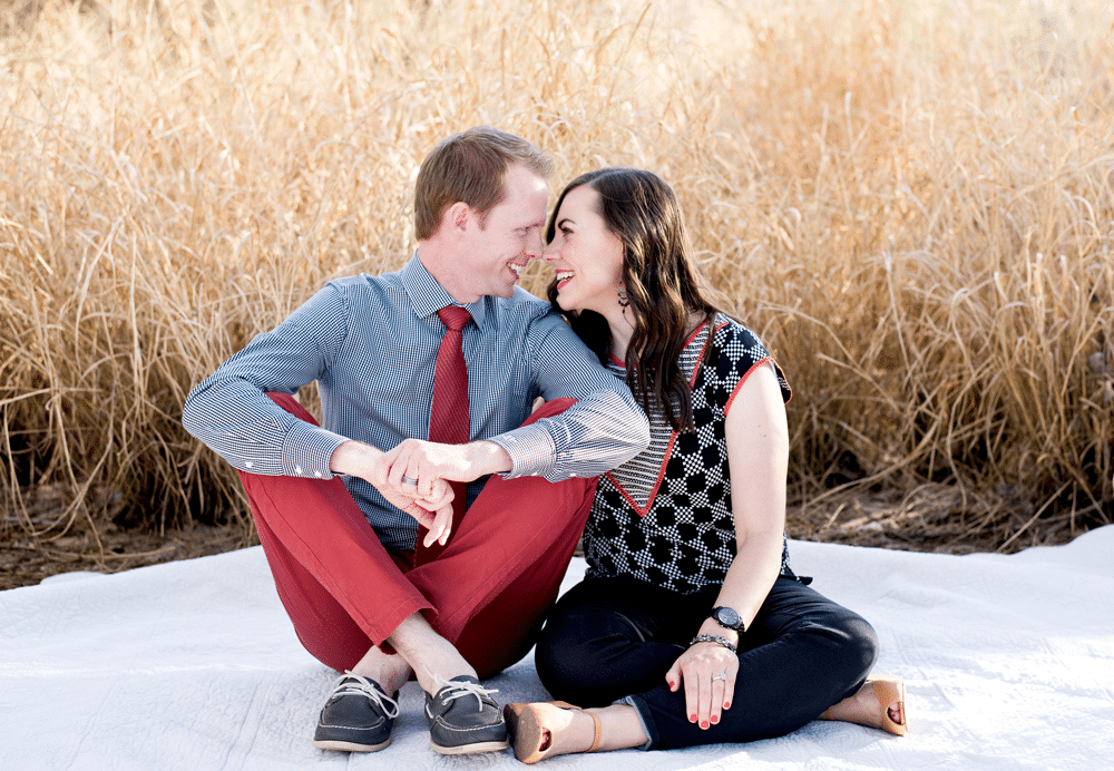 Cute anniversary pictures with couple sitting in a field on a picnic blanket. 