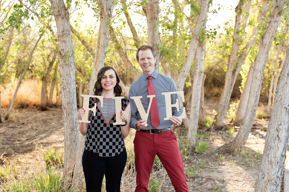 Couple celebrating their 5th wedding anniversary holding up letters to spell FIVE. 