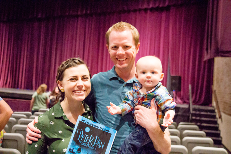 Young family standing in front of a curtain at a playhouse waiting to see Peter Pan. 