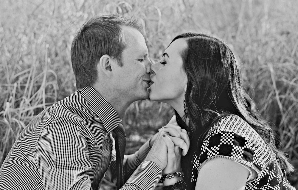 Black and white photo of a husband and wife facing each other and kissing. 