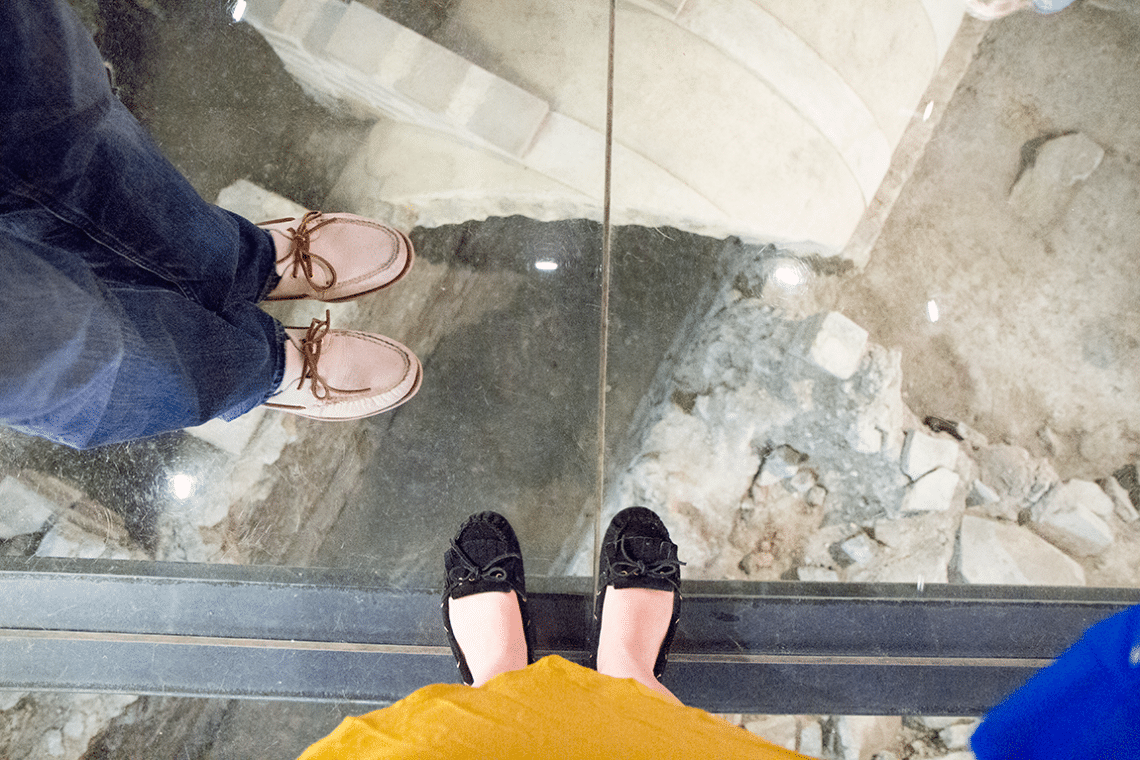 Two feet standing over glass casing showing the Toledo tunnel artifacts. 