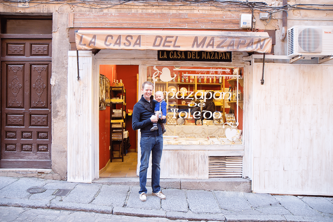 Dad and baby standing in front of La Casa Del Mazapan in Toledo Spain. 