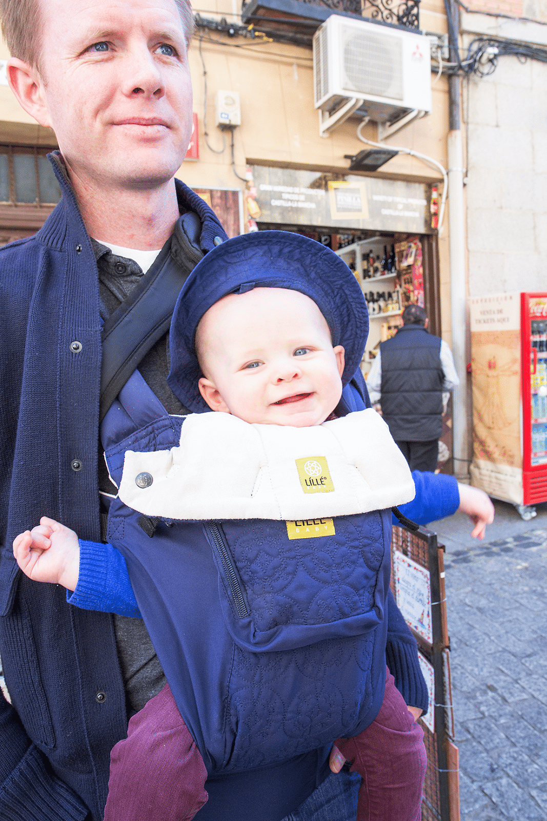 Baby smiling in a baby carrier outside of Toledo Spain. 