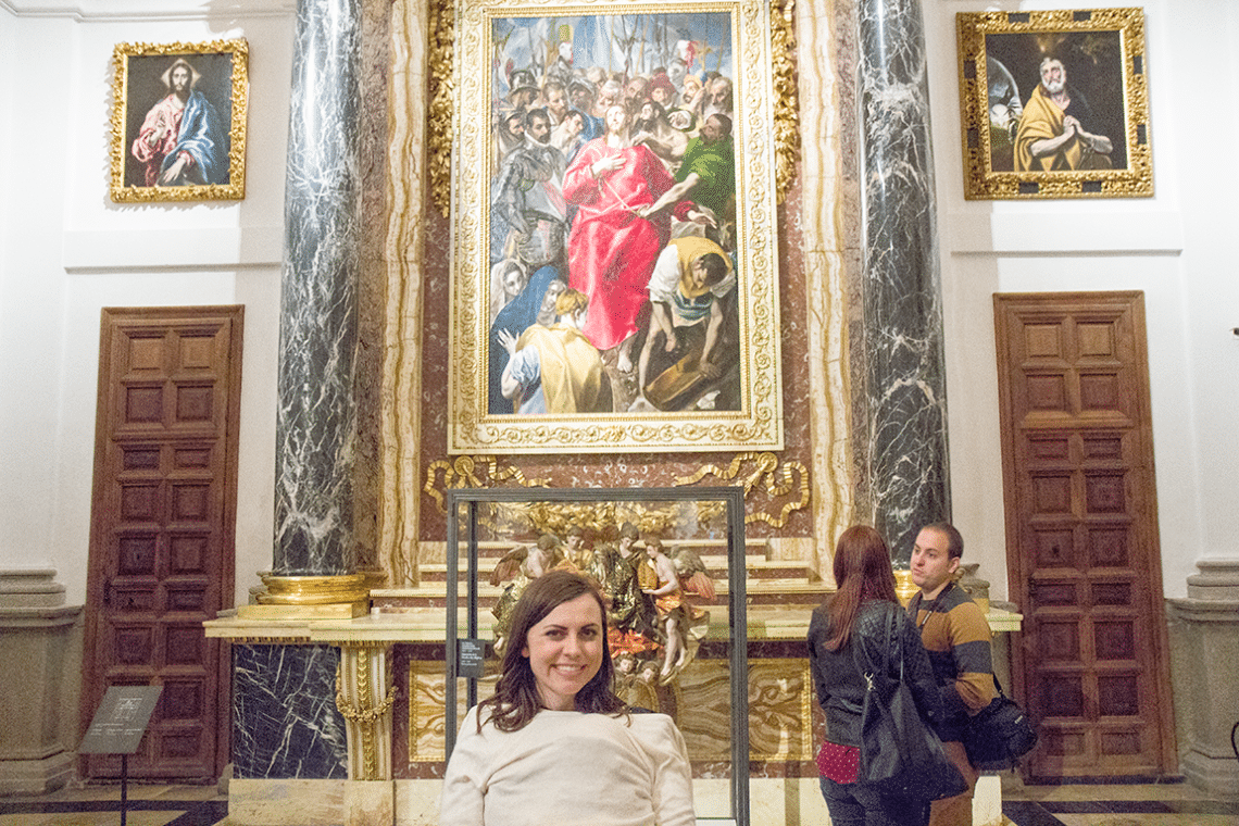 Woman smiling in front of painting of Christ in Toledo Cathedral in Toledo Spain. 