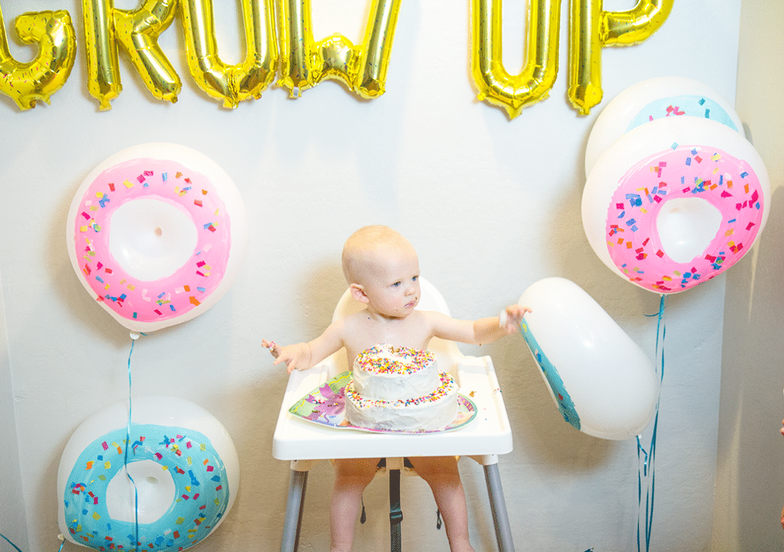 Baby's 1st birthday party with donut themed ballons and "Donut Grow Up" spelled in foil balloons behind them. 