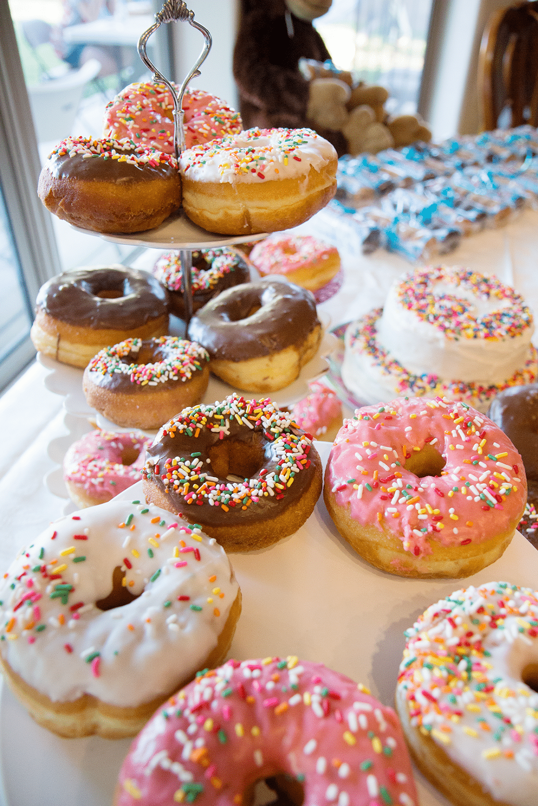 Multicolored donuts arranged on cake plates as a donut birthday party cake. 