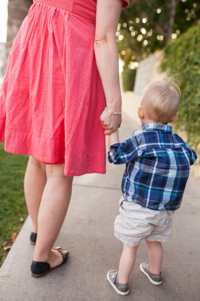 Mom holding toddler\'s hand. 