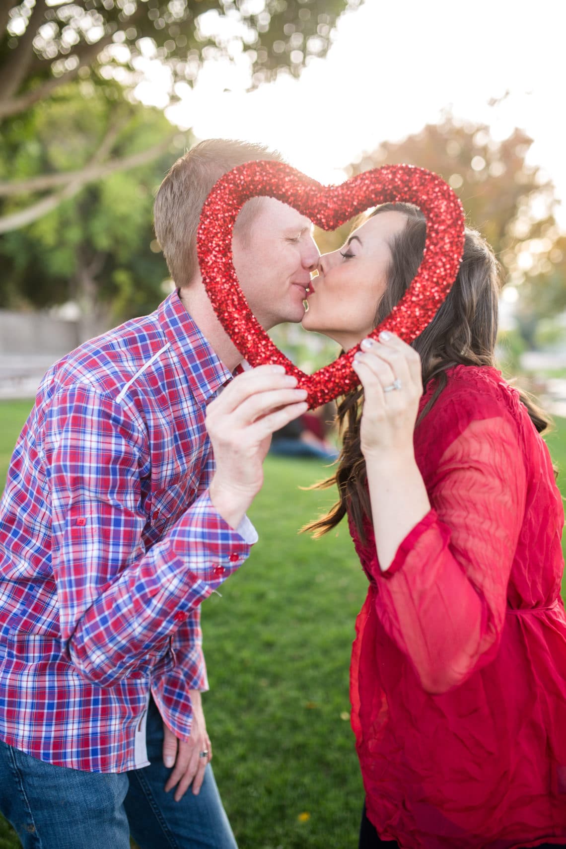 Couple kissing behind a heart decoration on a Valentine's Day Date. 