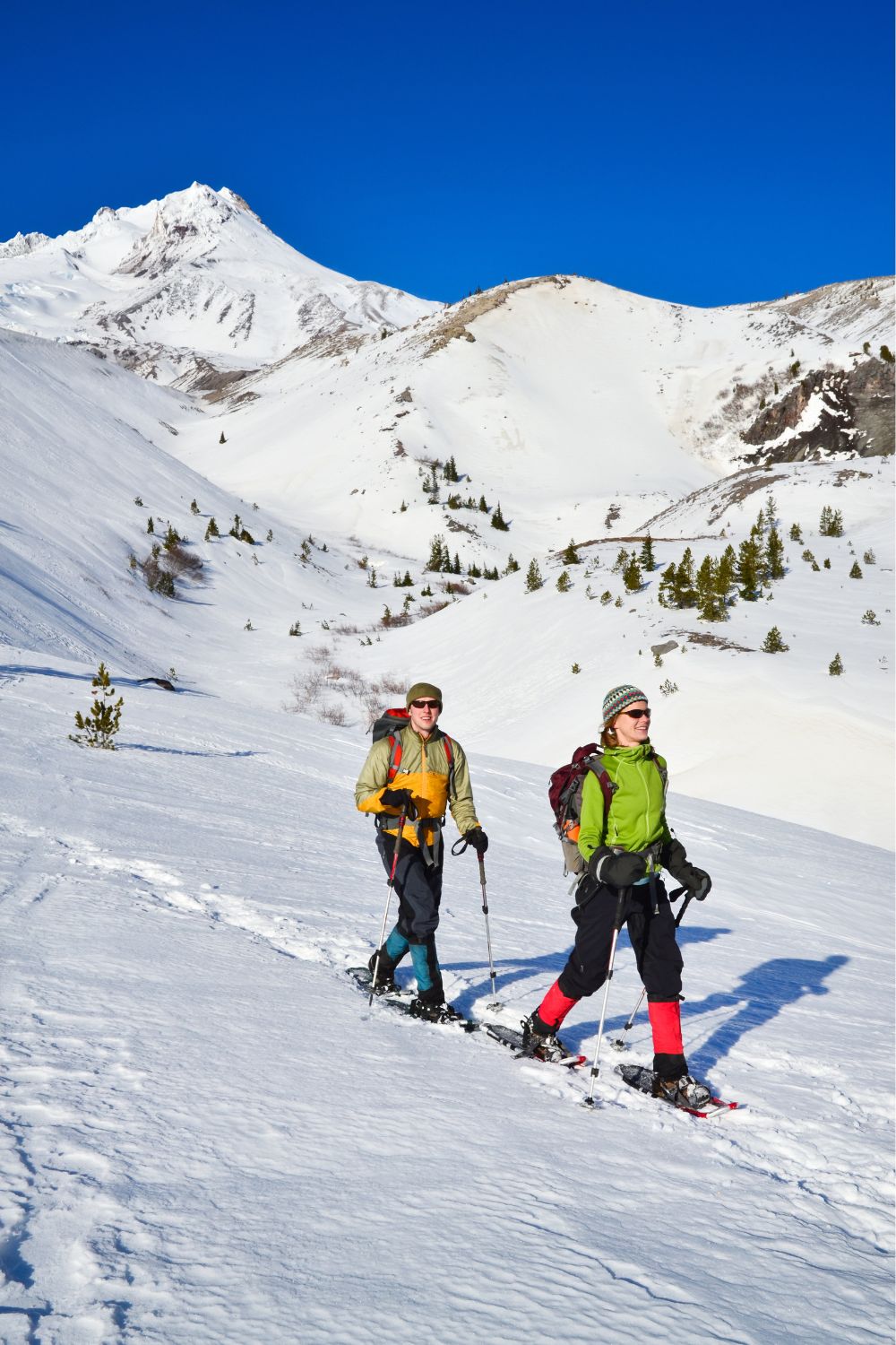 Couple out in the snow enjoying a snowshoeing Winter active date idea. 