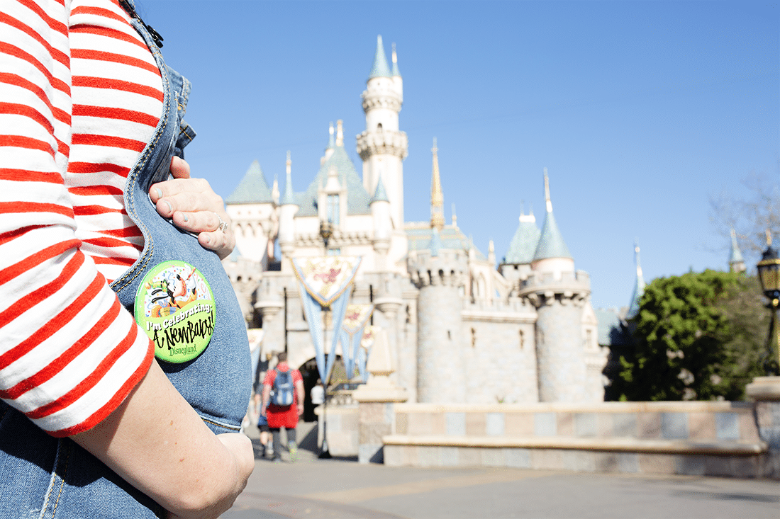Pregnant at Disneyland mom holding bump in front of castle sharing tips and tricks to make the most of your vacation. 
