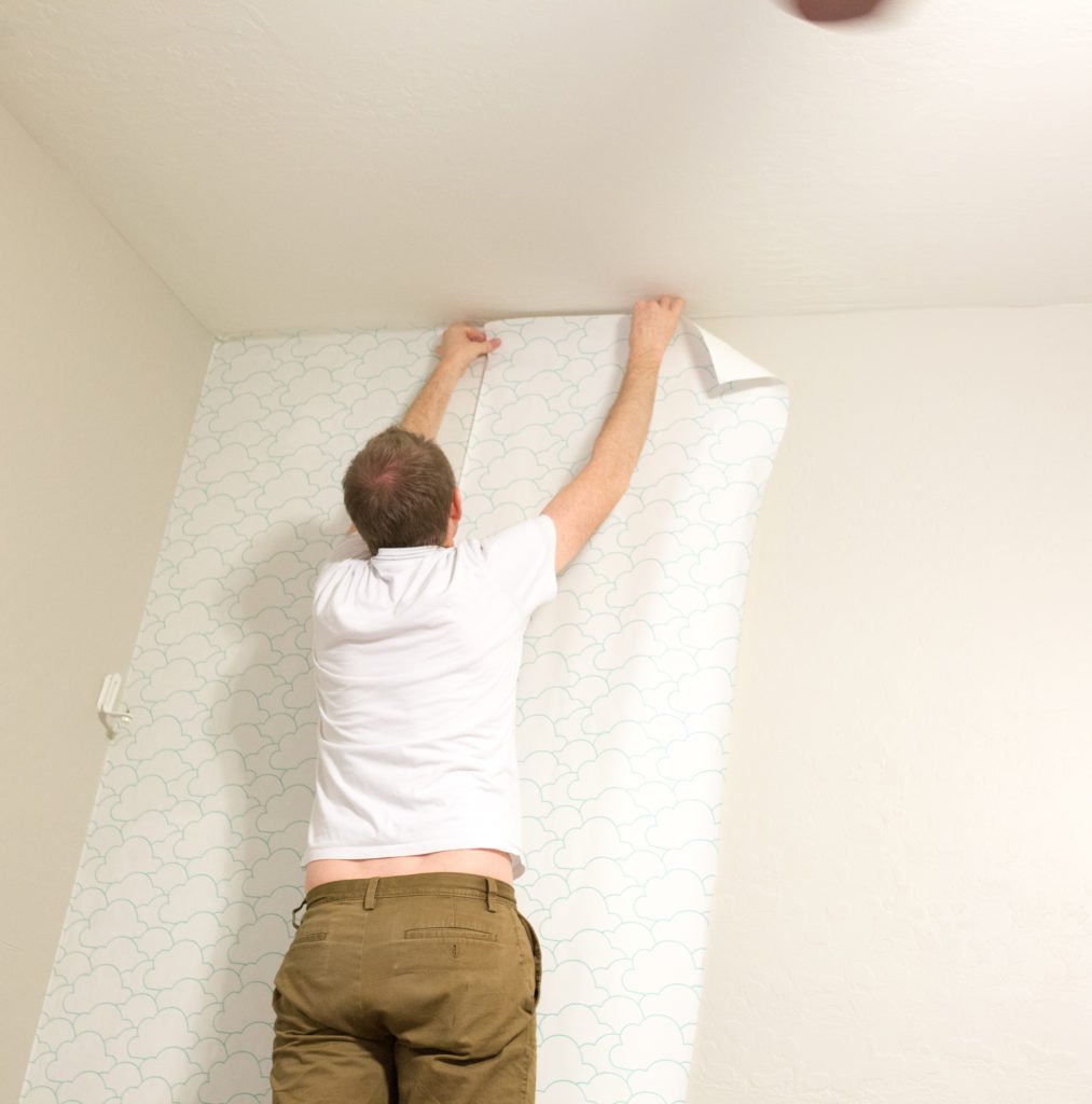 Husband hanging the Best Removable Wallpaper in a bedroom. 