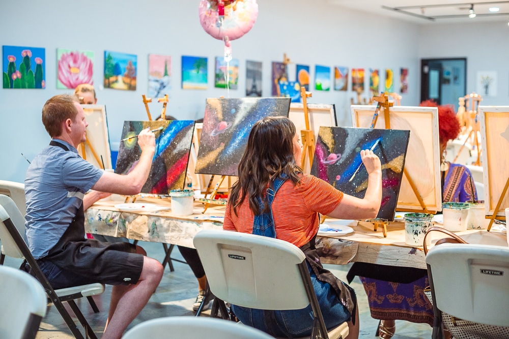 Couple having a paint night cute date idea painting on canvas. 