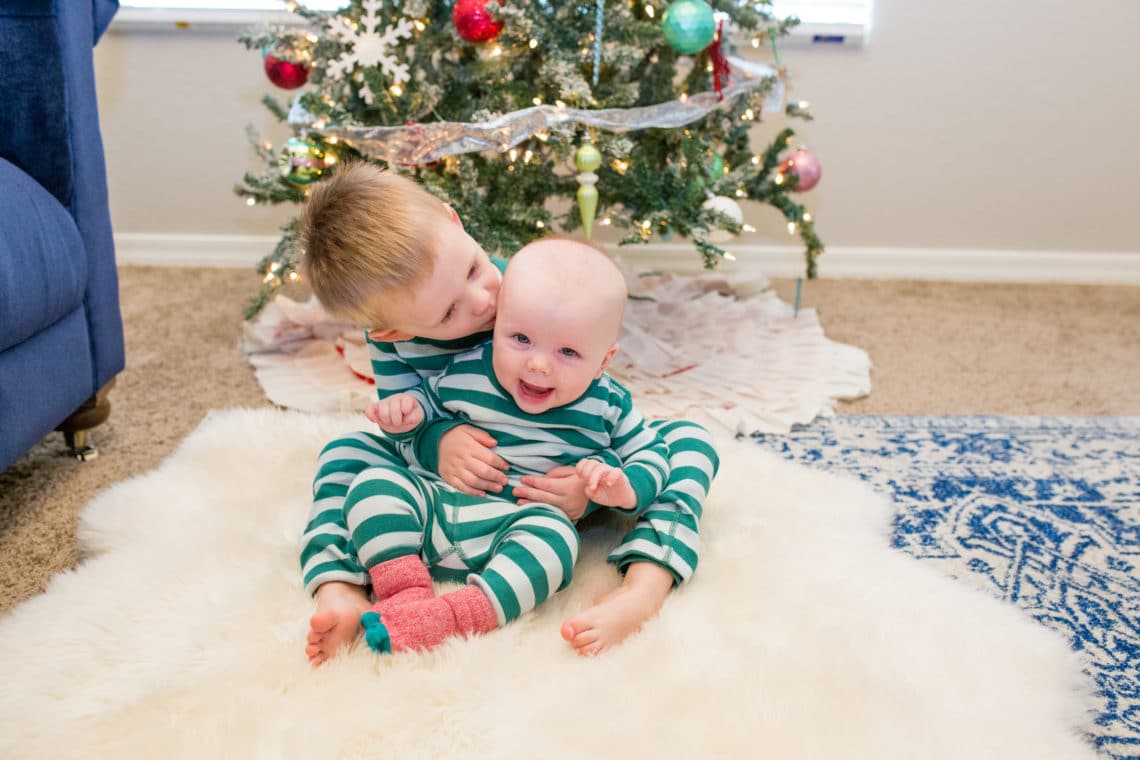 A baby and a toddler in green Matching Holiday Pajamas. 