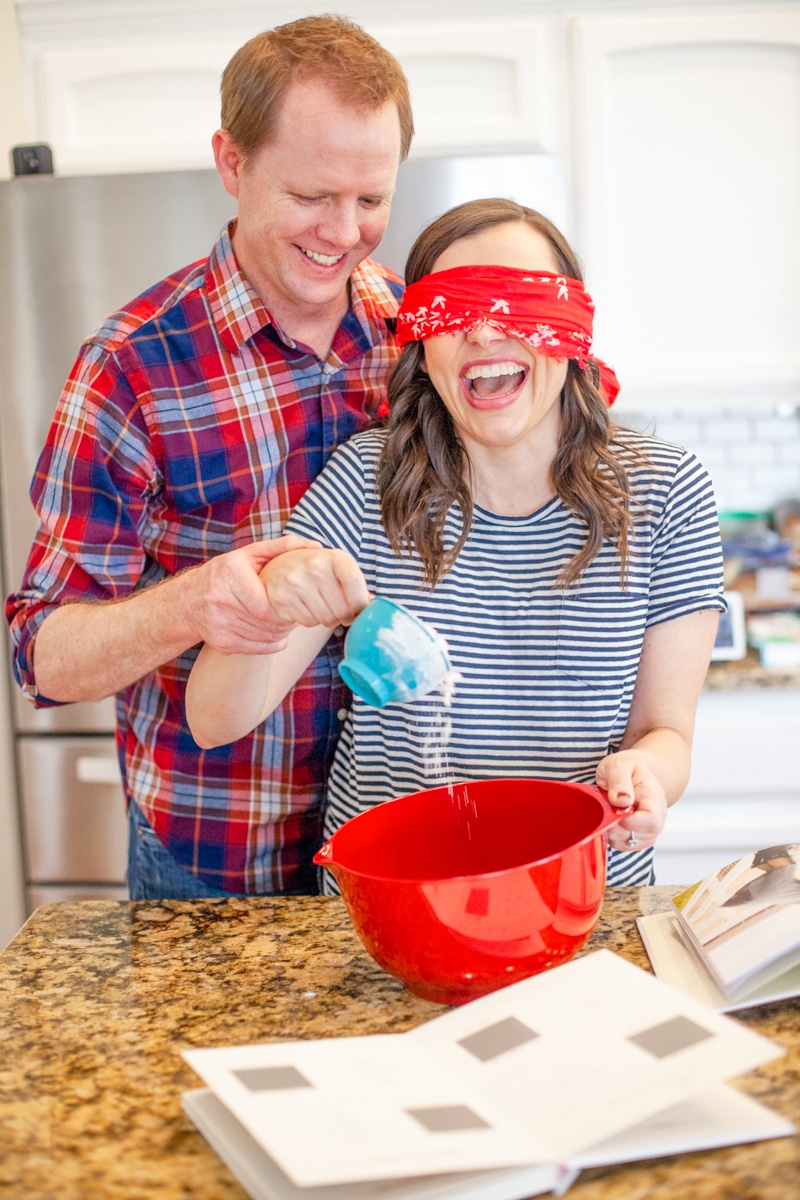 Husband helping wife pour flour into a mixing bowl for a baking date night. 