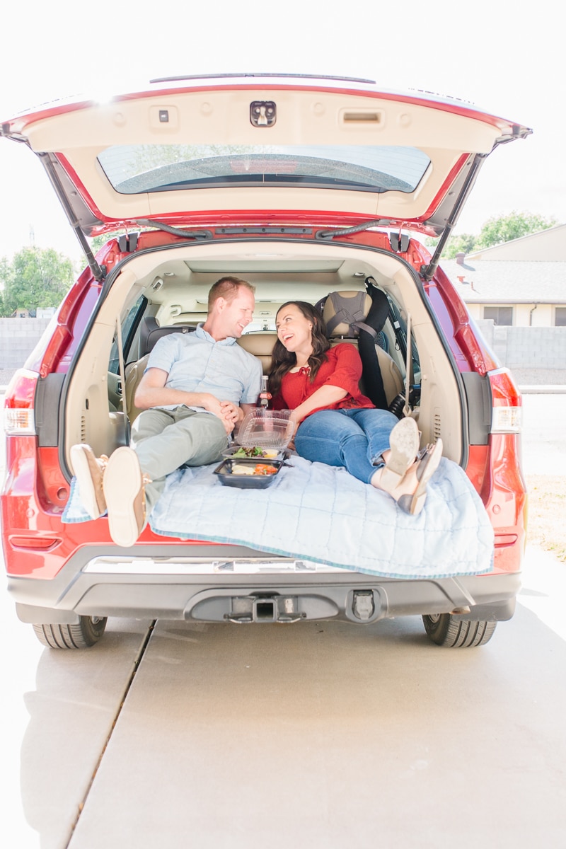 Car picnic date idea with couple enjoying a picnic in the back of their SUV. 