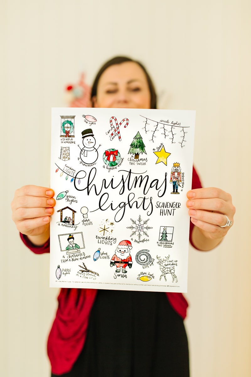 Mom holding a Free Christmas Lights Scavenger Hunt printable. 