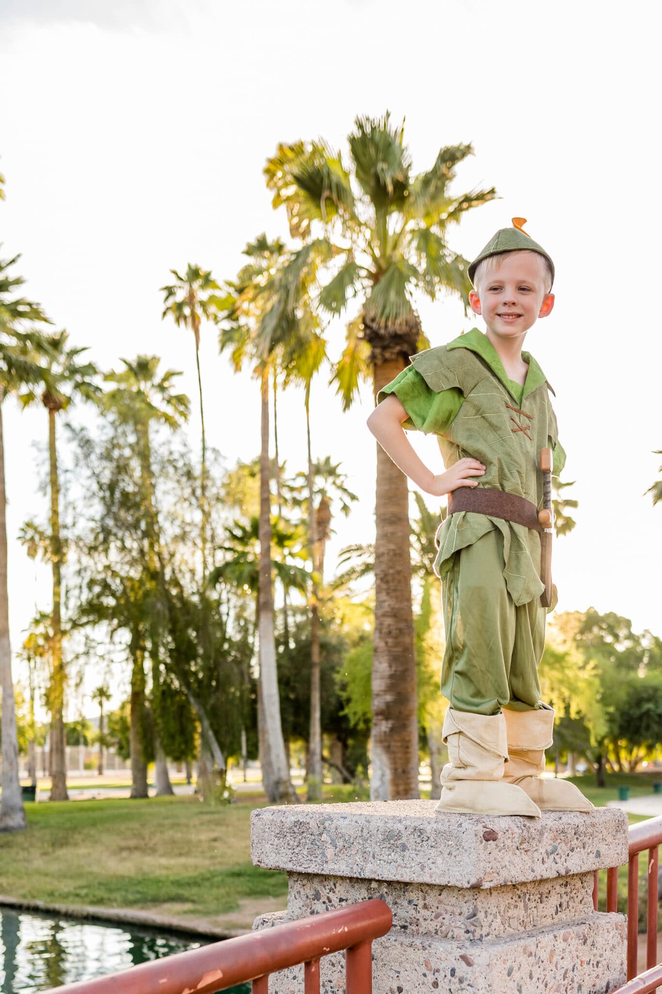 A boy modeling a Peter Pan Costume with palm trees behind him. 