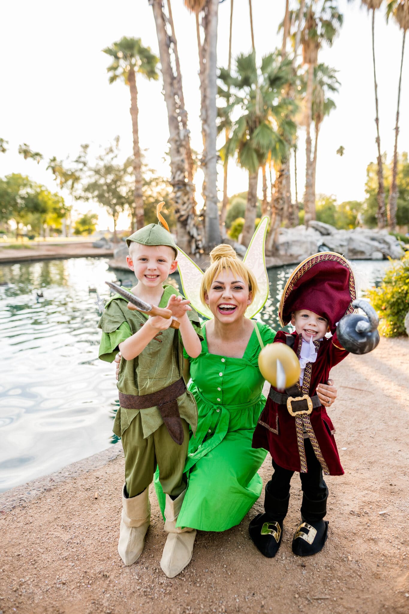 A mom dressed as Tinkerbell with her two boys dressed as Peter Pan and Captain Hook characters in Peter Pan family costumes. 