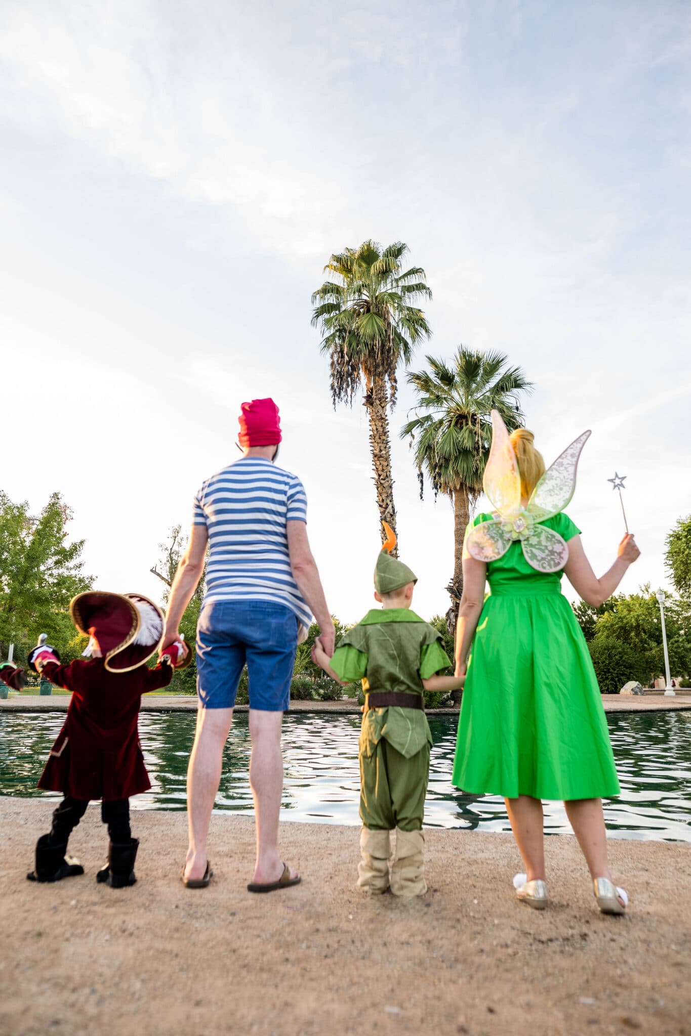 A picture of a family from behind holding hands modeling a Peter Pan Family Costume. 