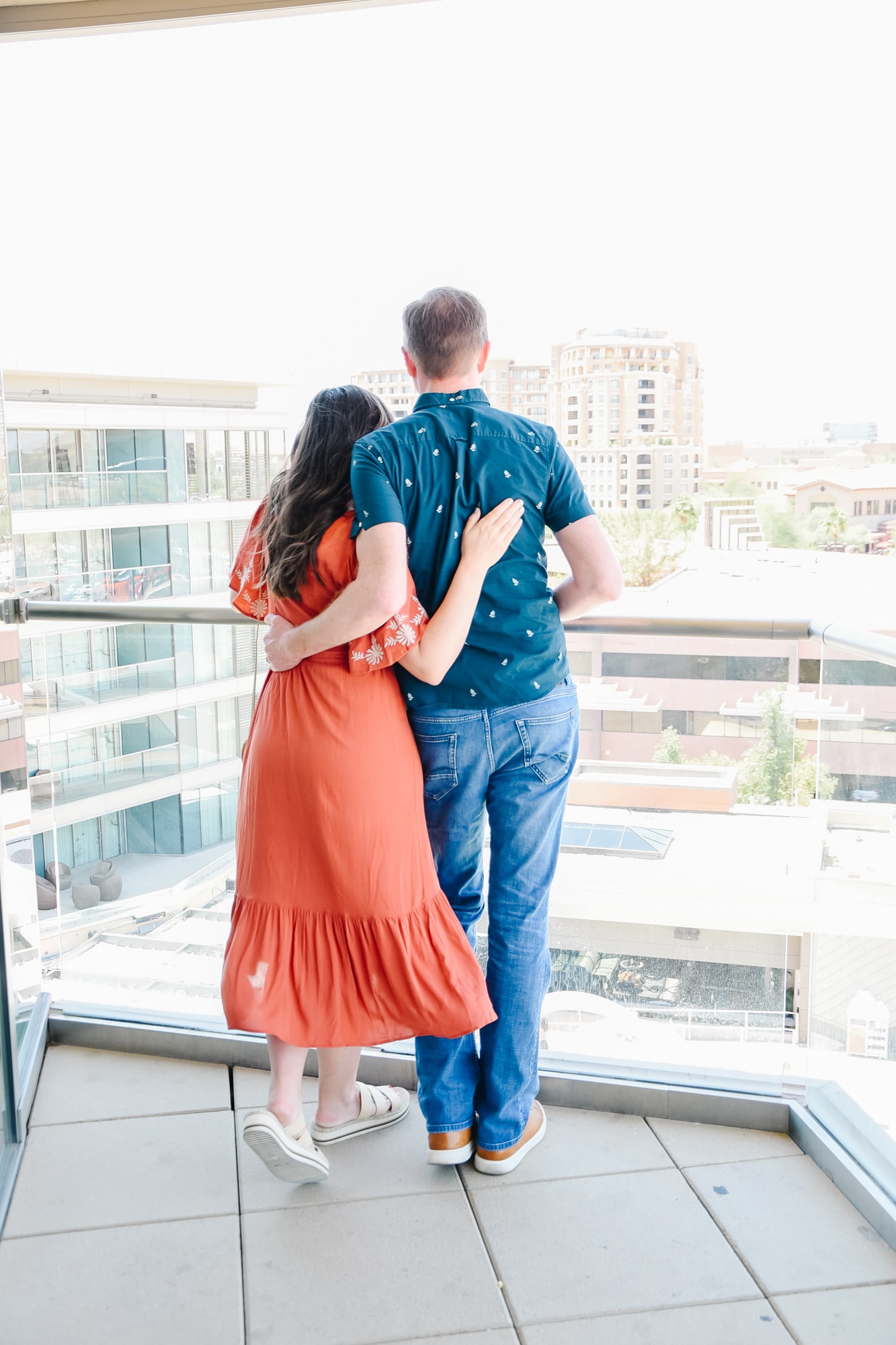 Couple standing on hotel balcony getting ready for some Hotel Date Night Ideas. 