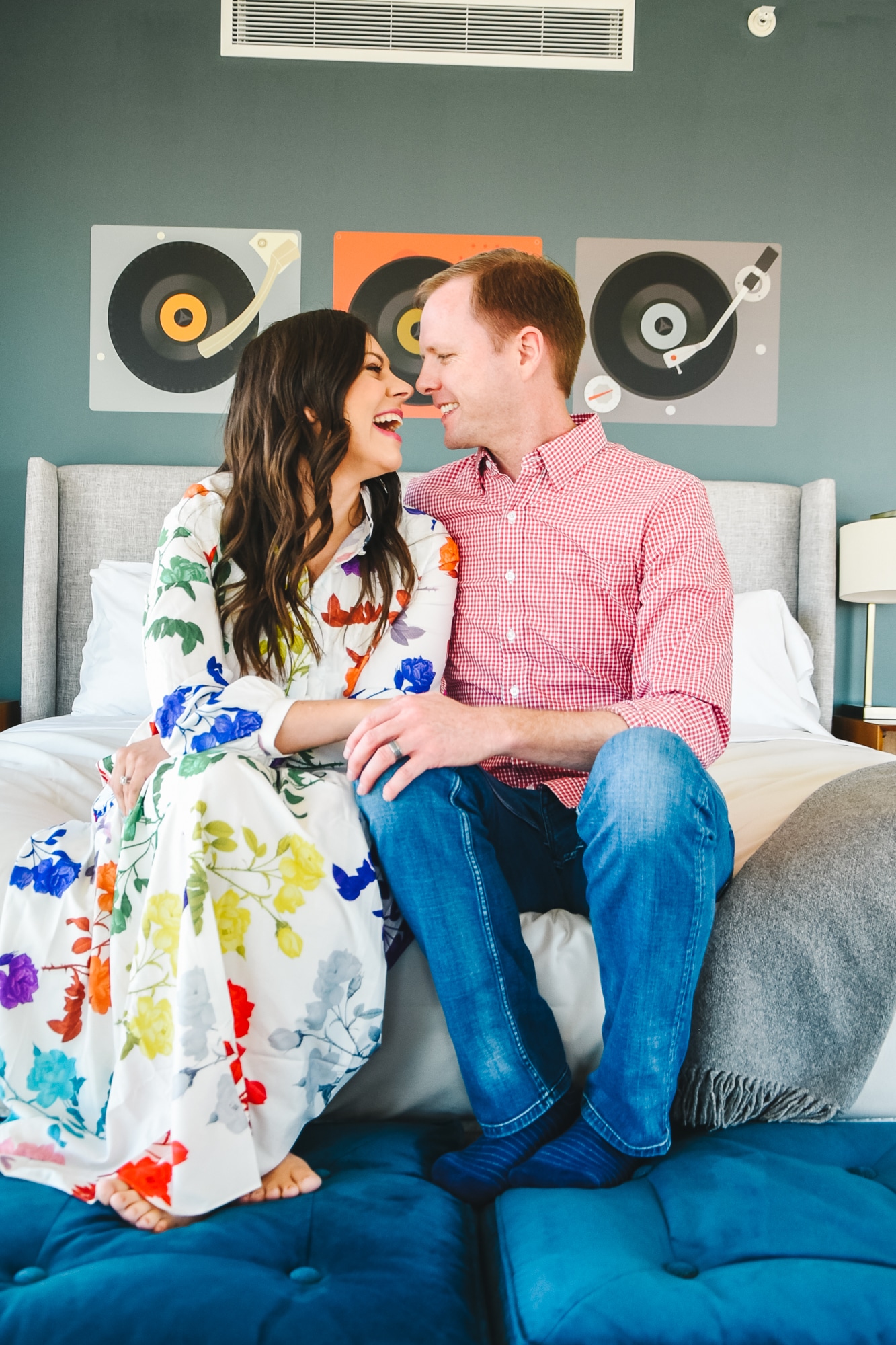 Couple sitting on a hotel bed getting ready for some Hotel Date Night Ideas. 