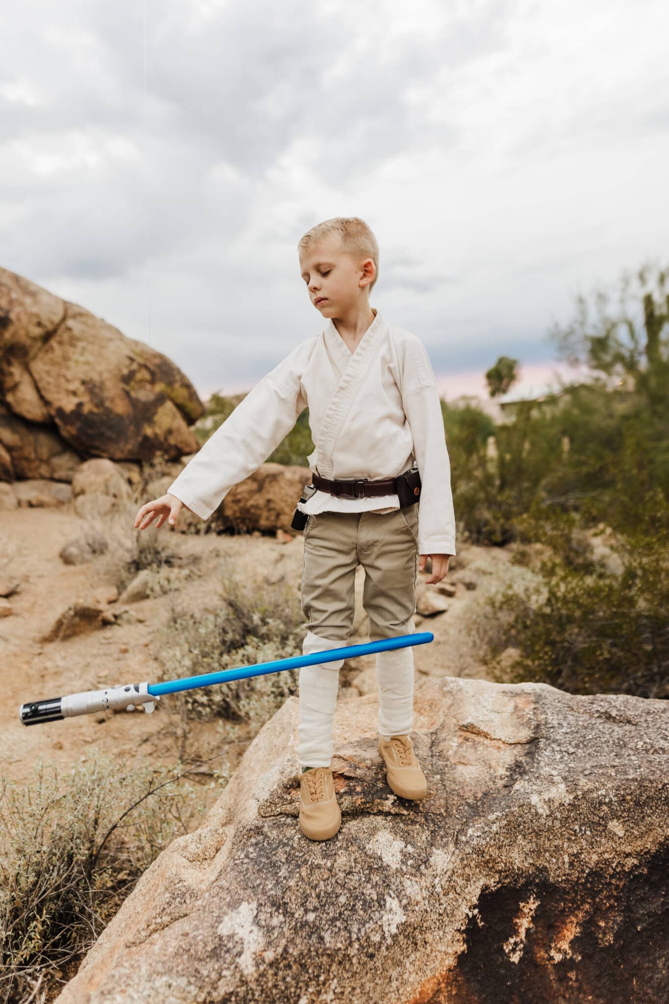 A kid calling a lightsaber to come to him in his Luke Skywalker costume for a Star Wars family costume. 