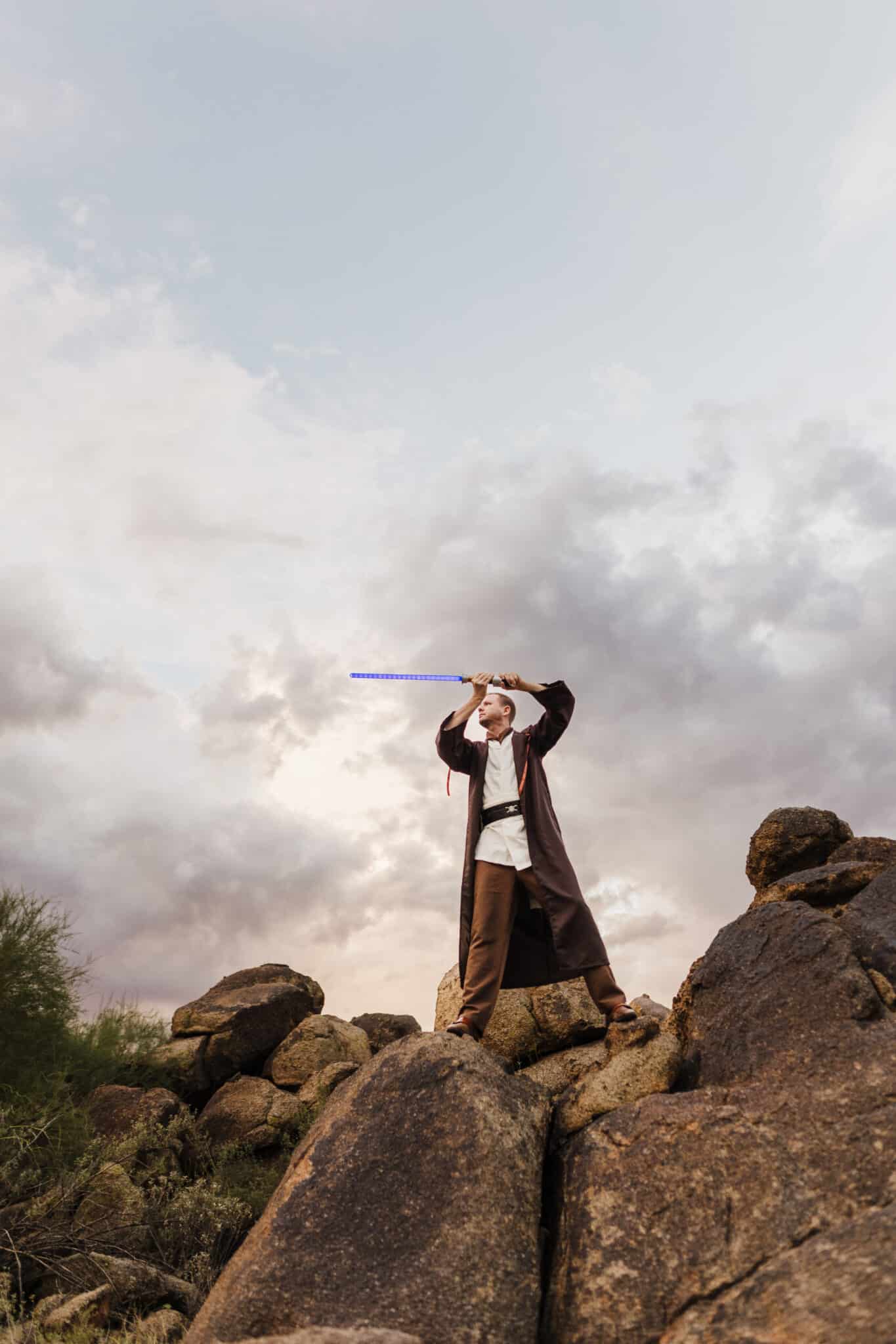 Man on dessert rocks showing his Obi Wan Kenobi Costume. 