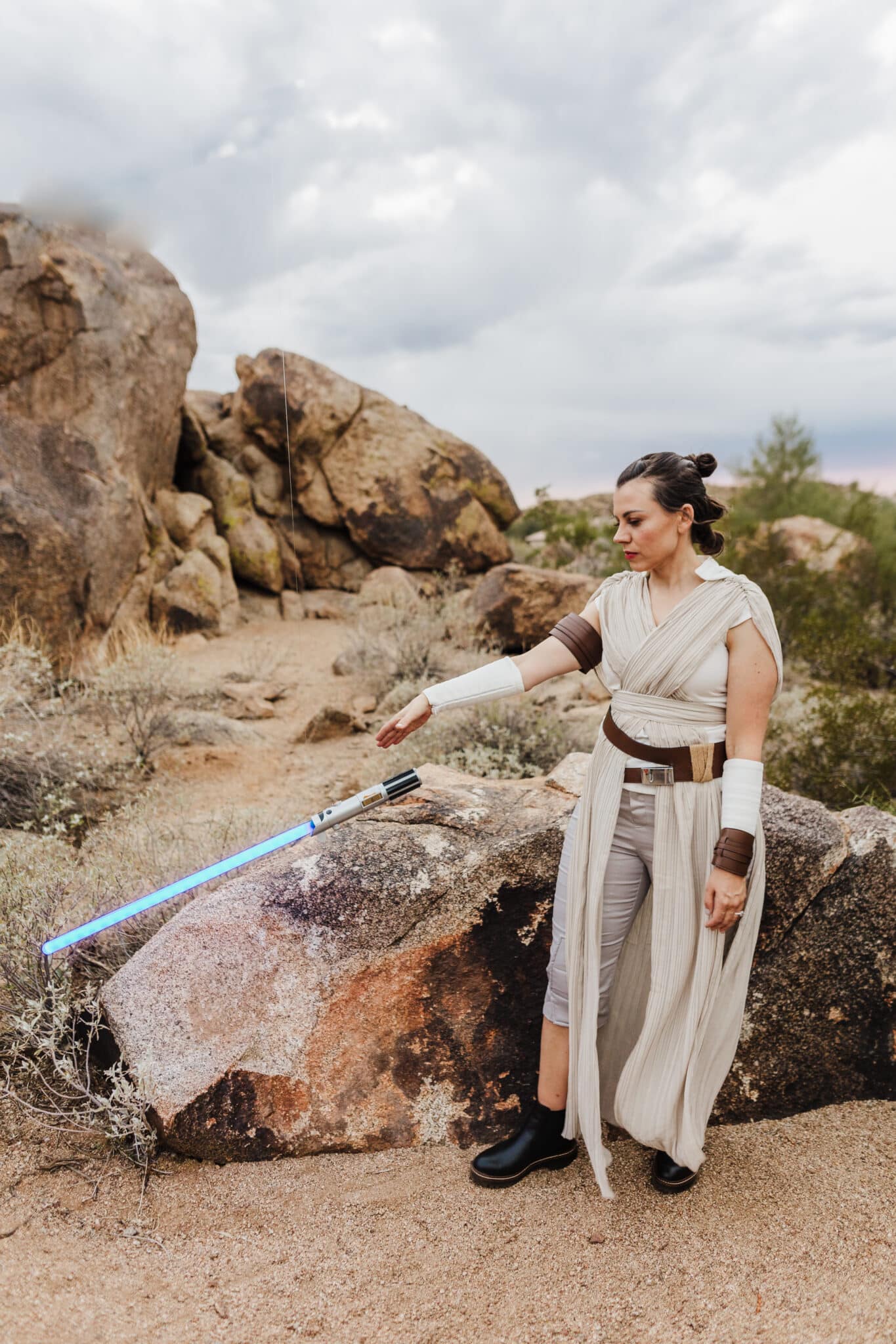 A woman in a Rey from Star Wars Costume calling a lightsaber on a fishing line to come to her. 