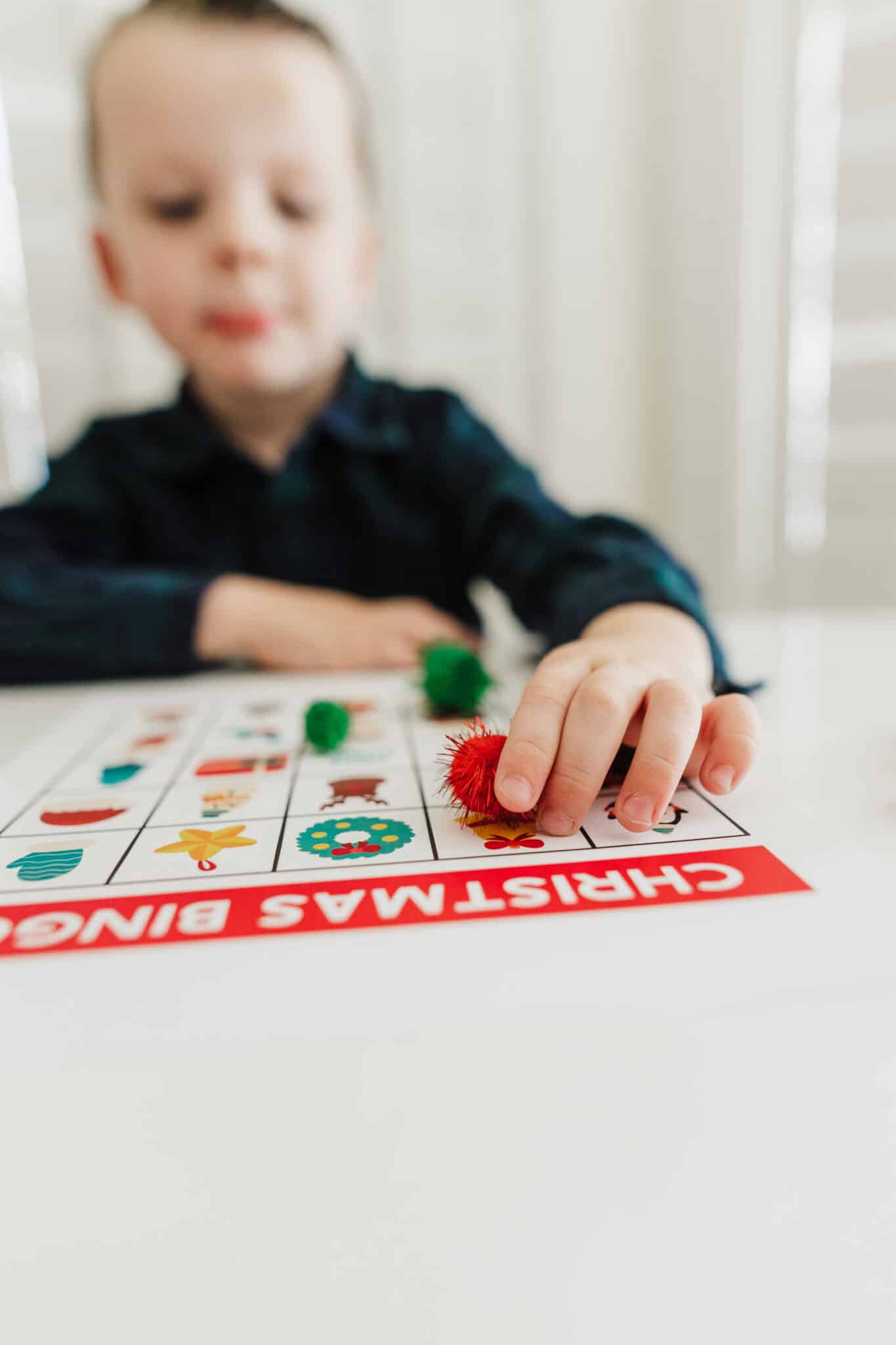 Christmas BINGO cards for kids with a preschooler playing Christmas BINGO.