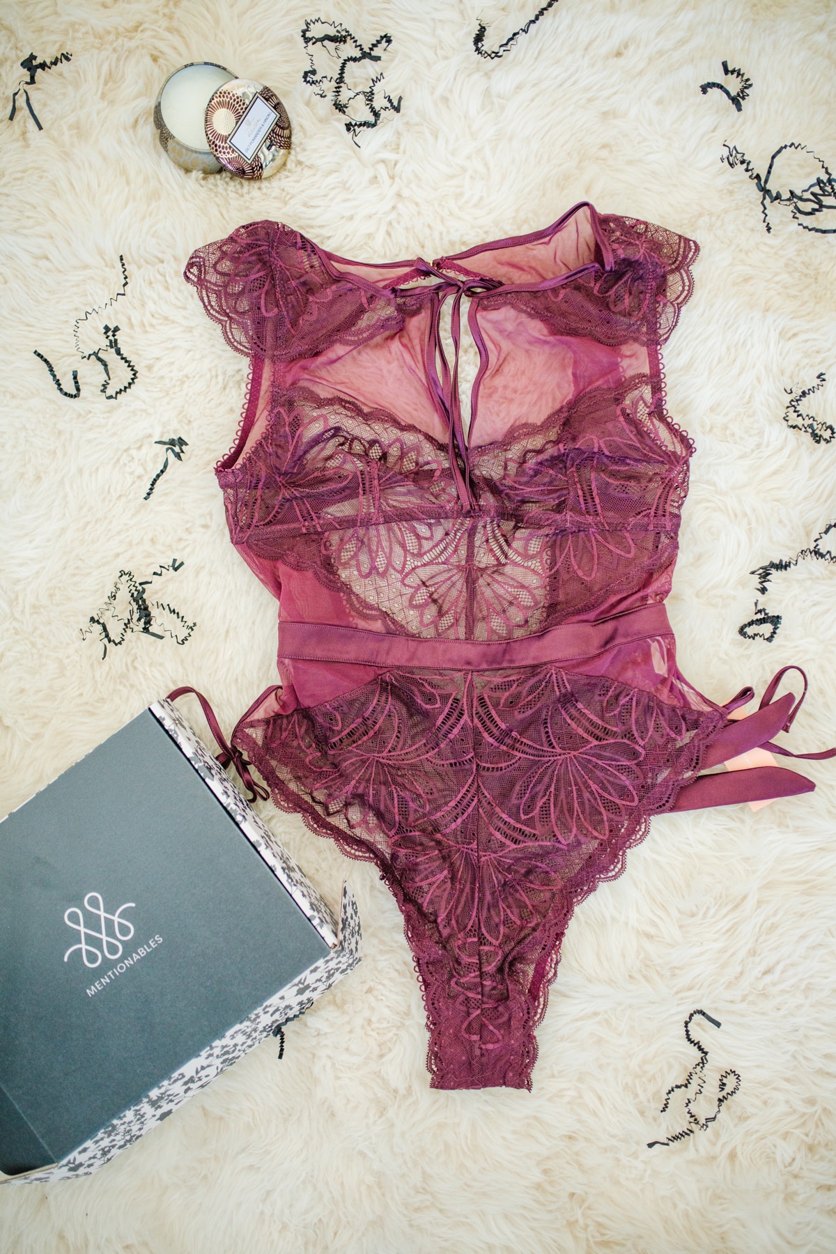 Purple lace Size Inclusive lingerie by Mentionables on a fuzzy rug with a lingerie box next to it. 