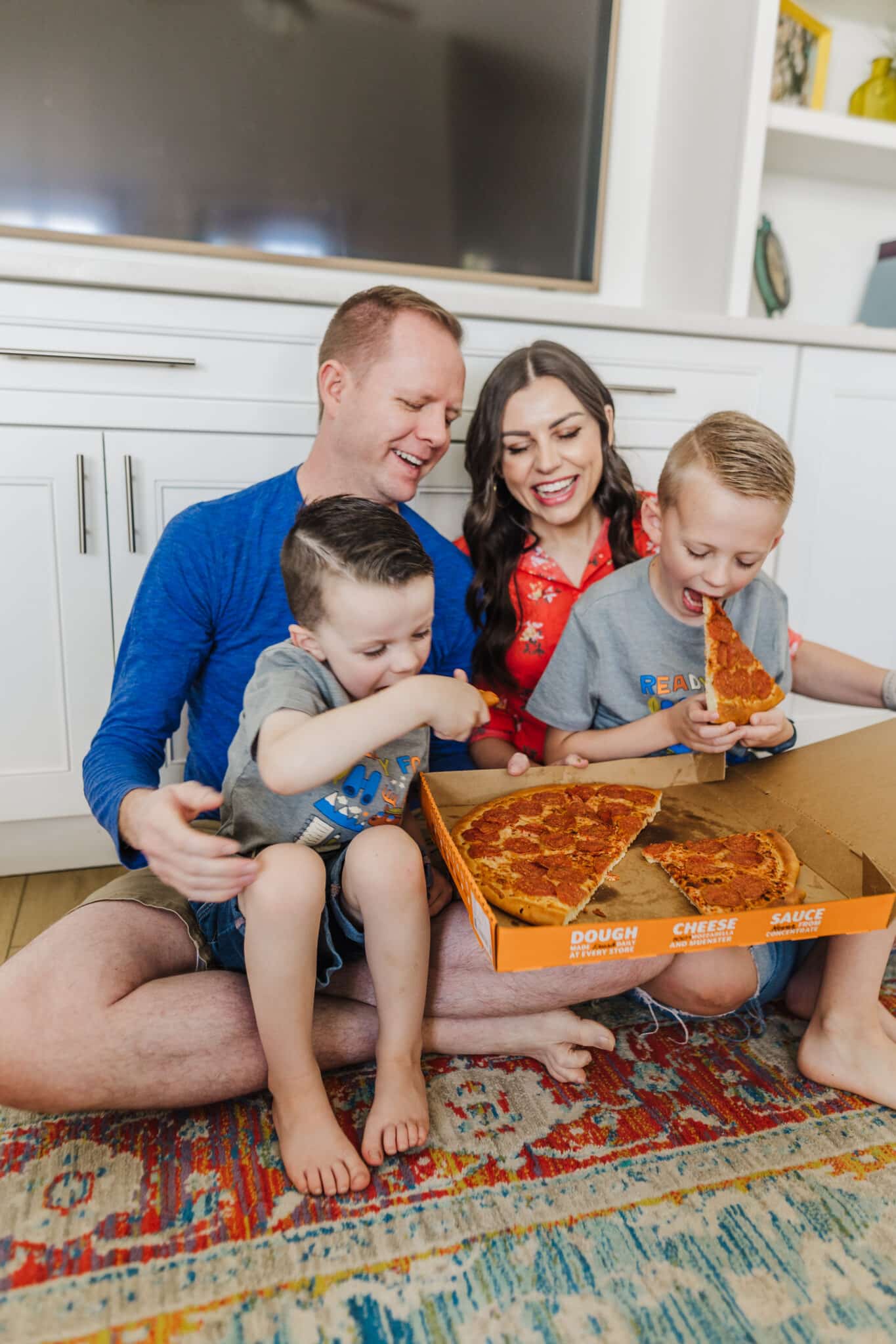 Mom and dad with two kids holding a pizza box ready to do thing things to do at night with kids together. 