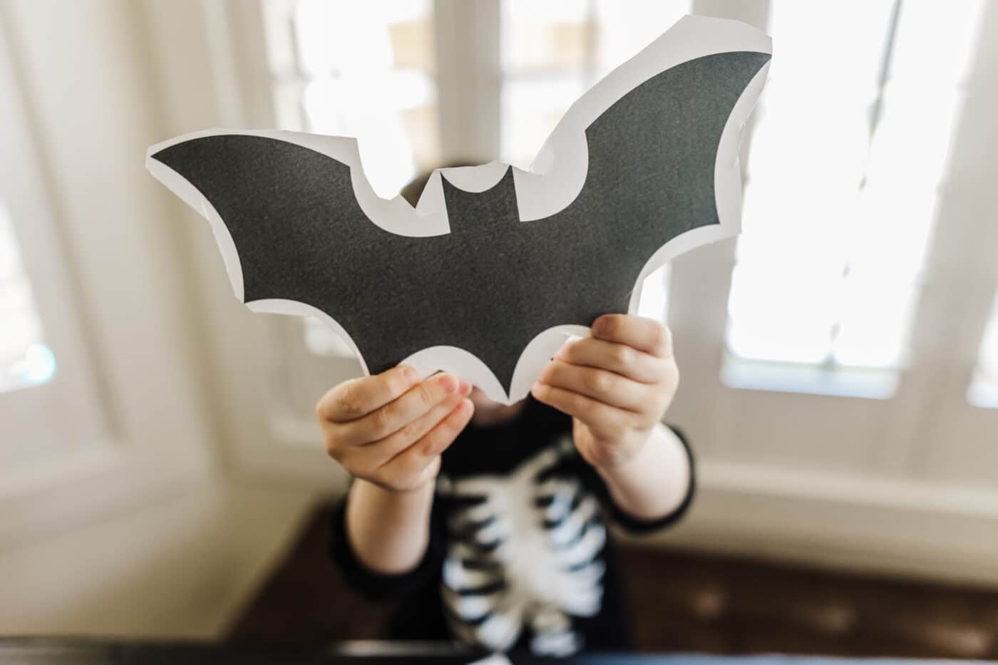 Child holding a cut out printable bat template. 