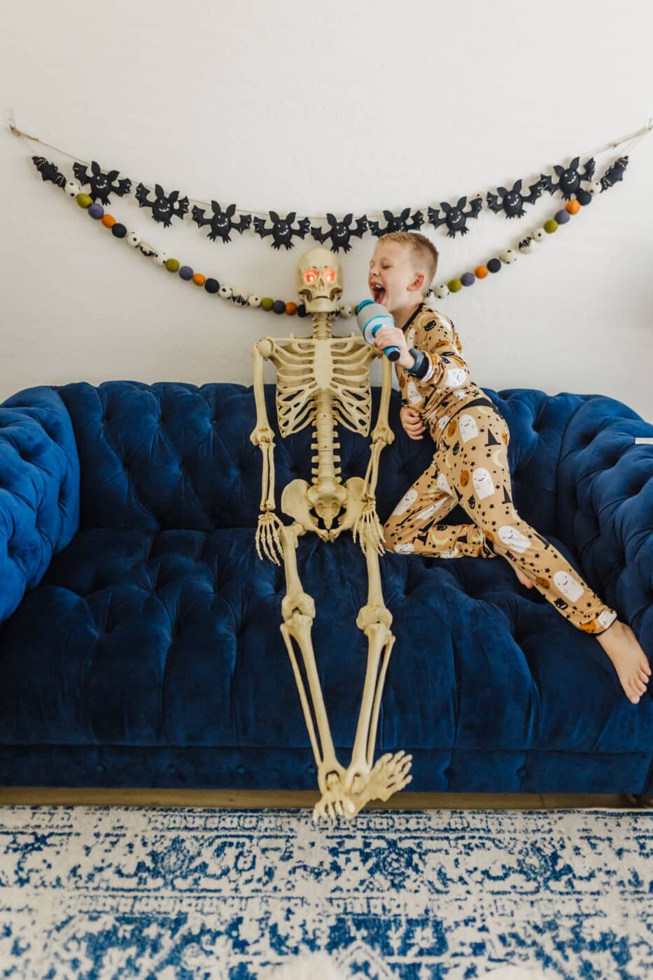 Kid singing fun Halloween songs for kids with a skeleton and play microphone. 