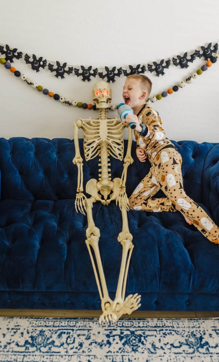 Kid singing fun Halloween songs for kids with a skeleton and play microphone.