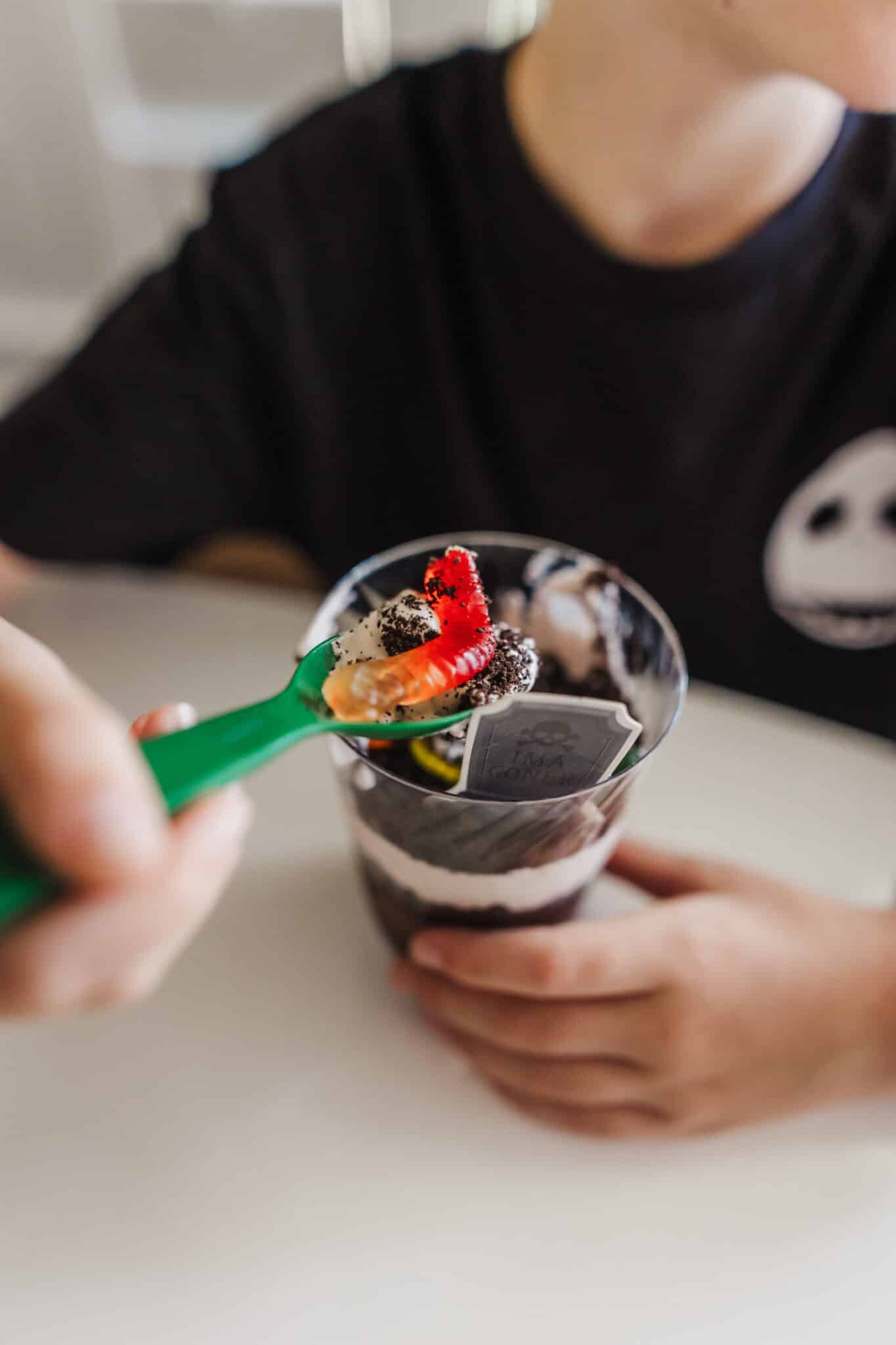 A kid about to eat a spoonful of Halloween Dirt Pudding Cups. 