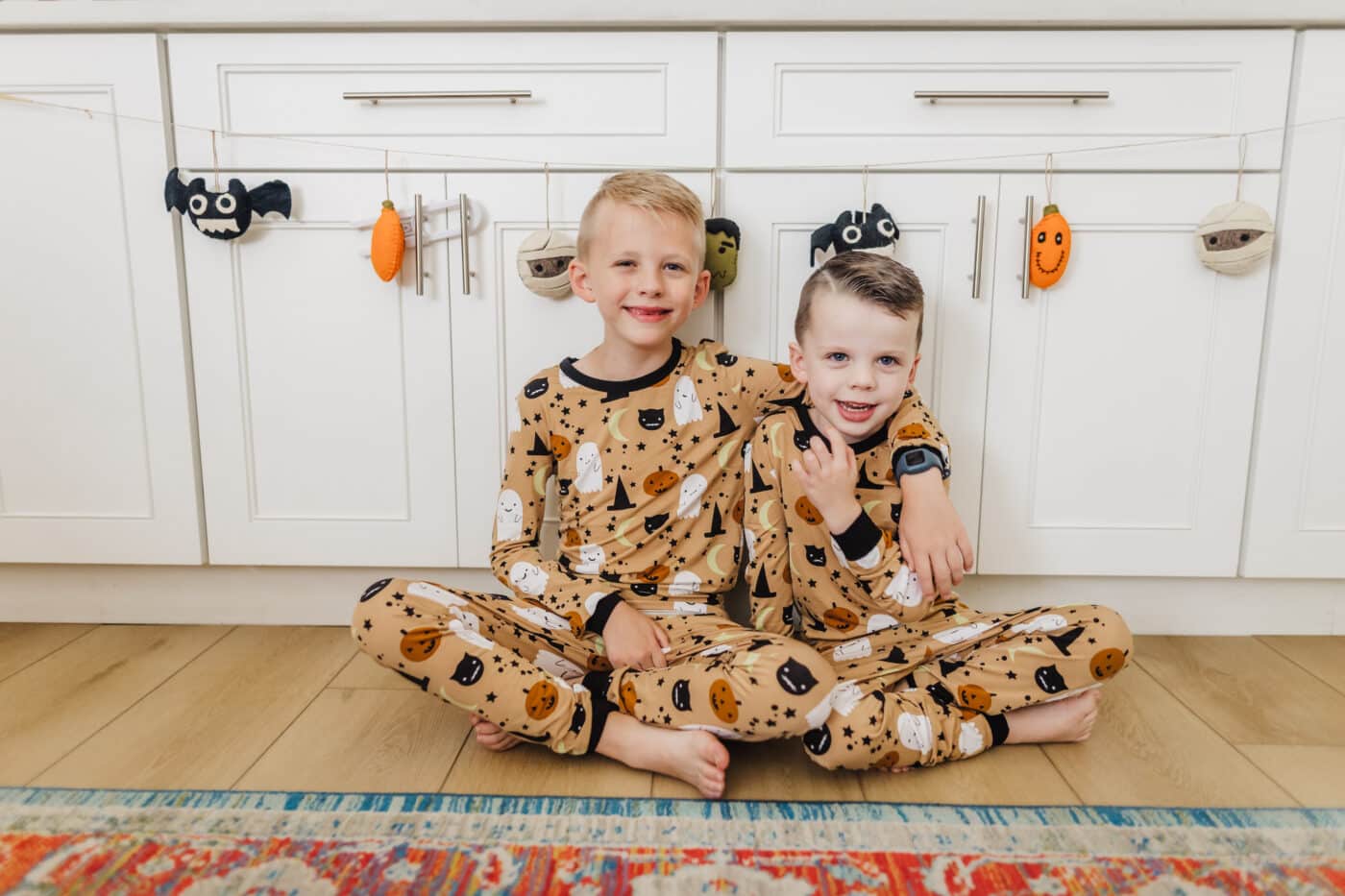 Two boys sitting on the floor in cute Halloween pjs for kids. 