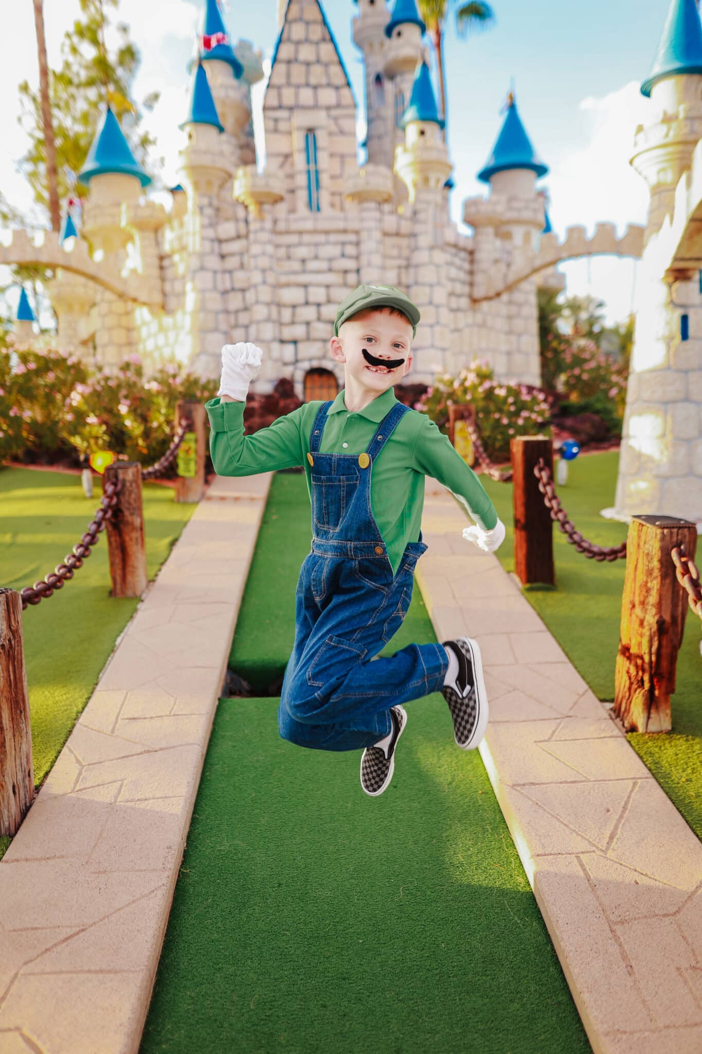 Boy jumping in a Mario Brothers Luigi Costume. 