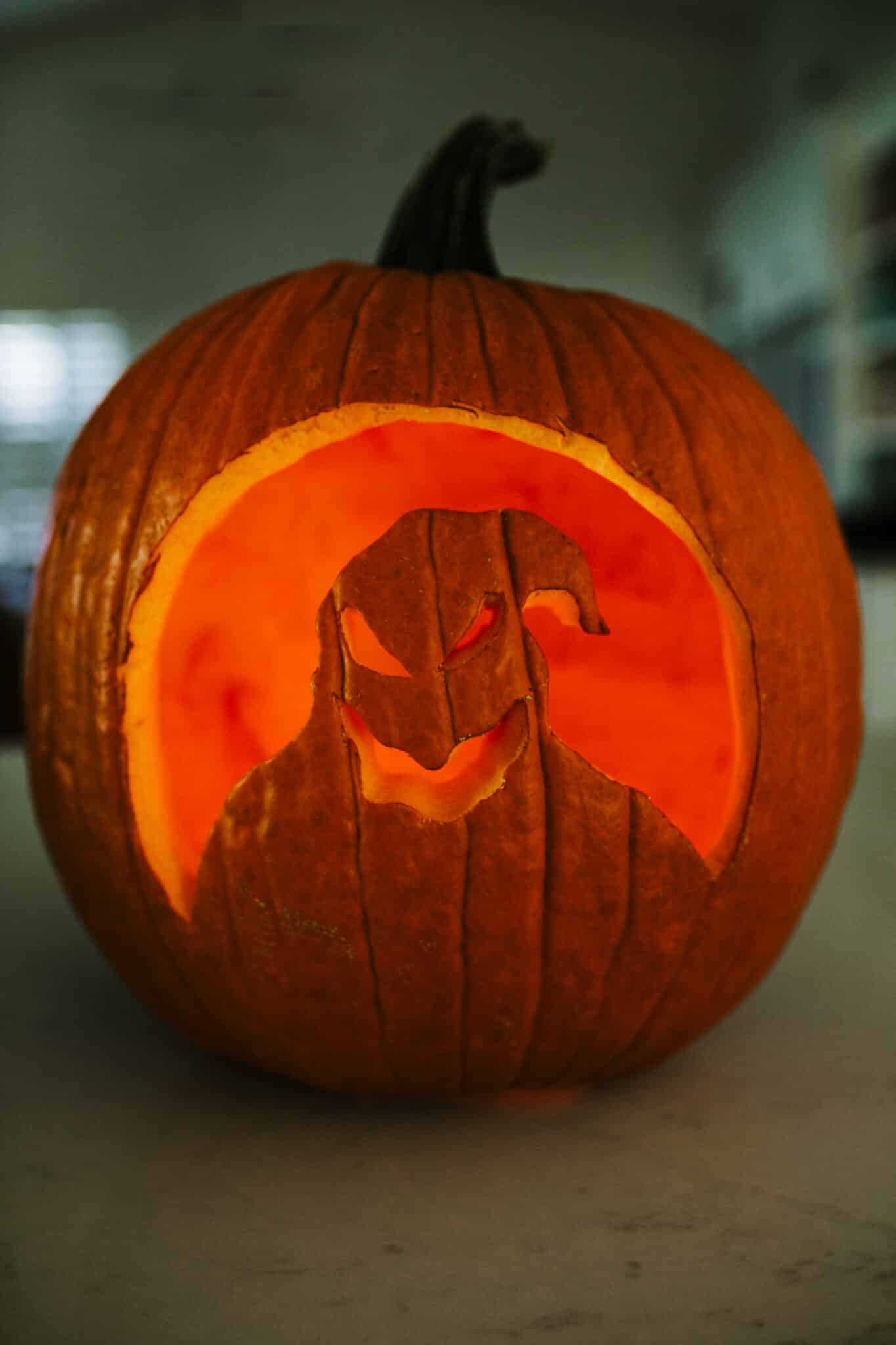 Oogie Boogie jack o lantern with a candle illuminating the pumpkin carving design.