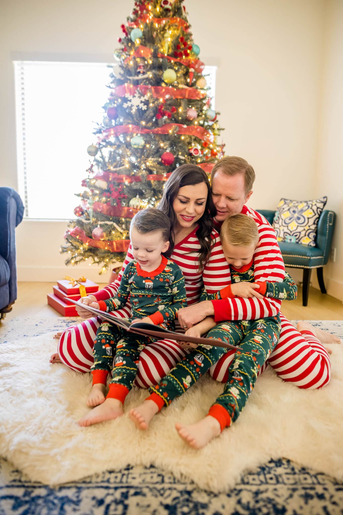 Family in front of Christmas tree in Christmas pajamas. 