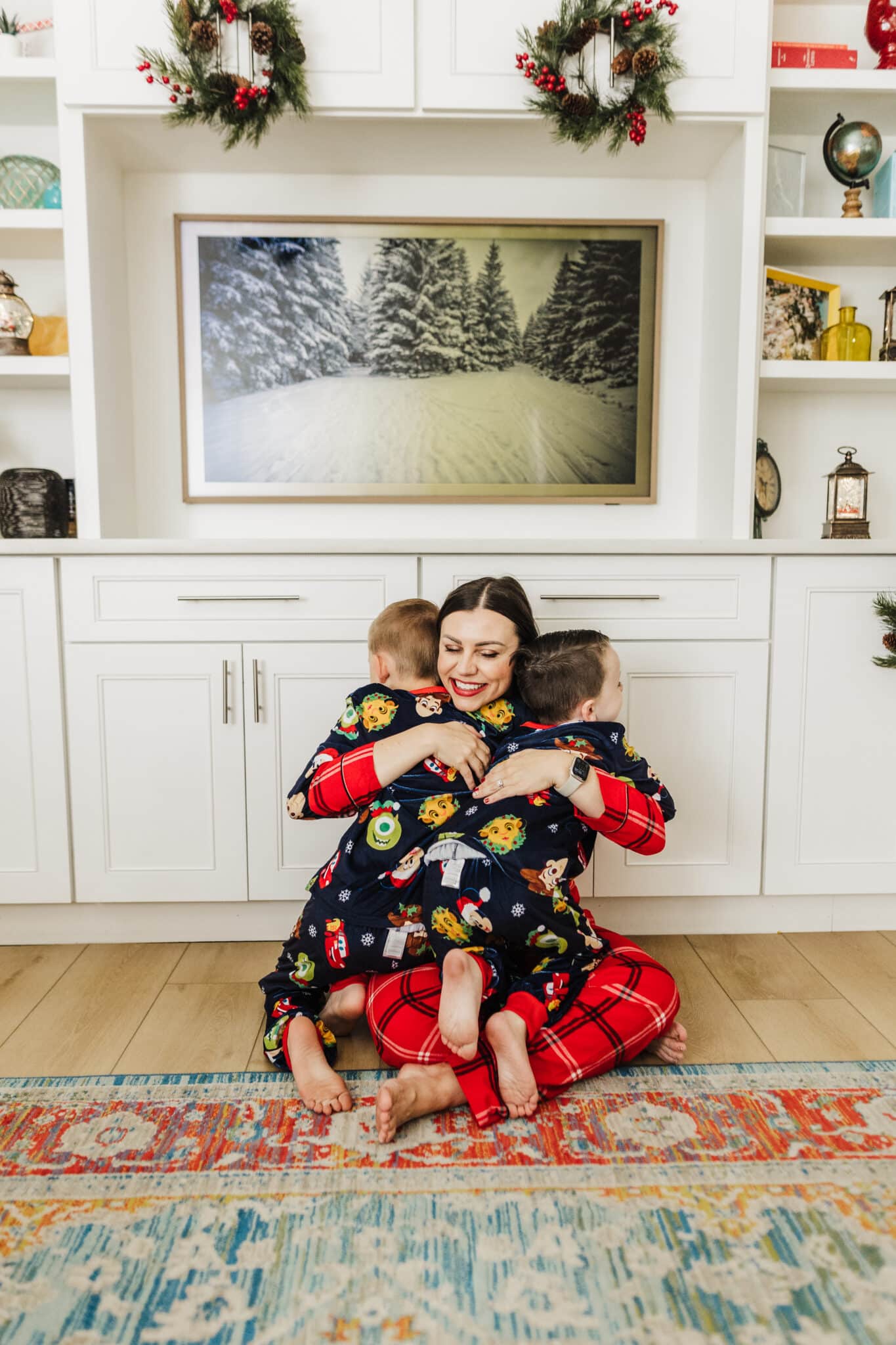 Mom hugging kids in Disney Christmas pajamas. 