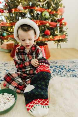 Kid in Christmas pajamas checking out the best stocking stuffers for kids.