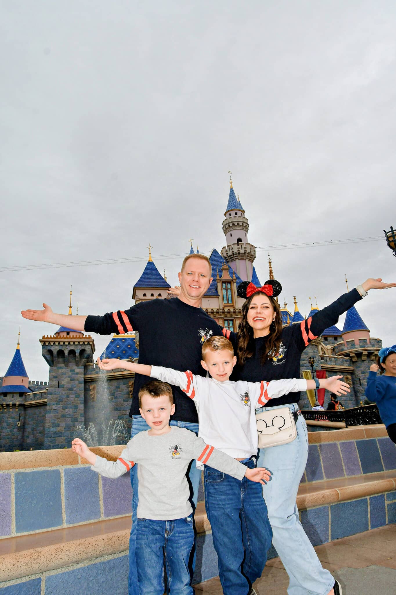 Family sharing their Disneyland outfits wearing matching Disneyland Spirit Jerseys in front of the castle. 