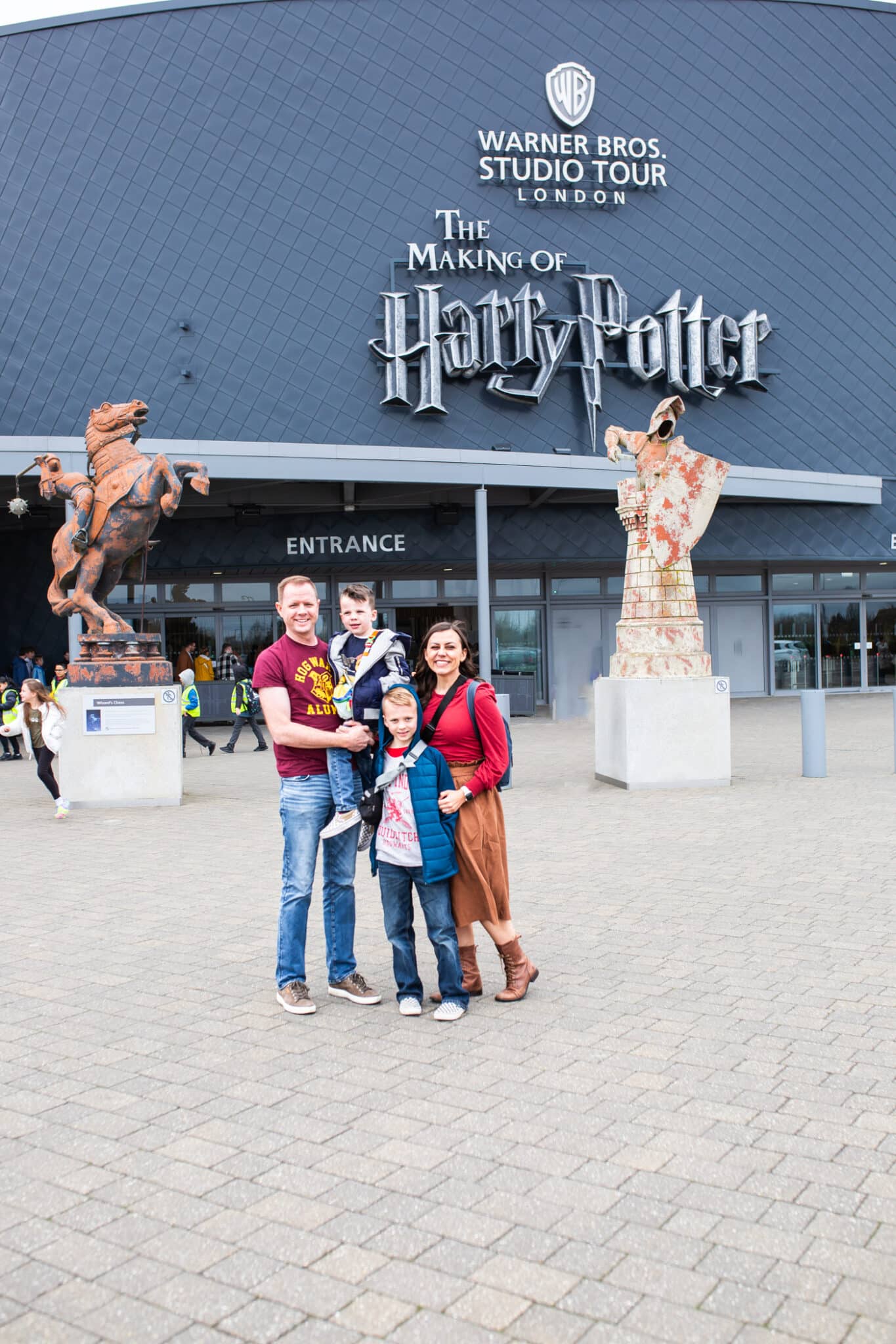 A family standing in front of the Warner Bros Studio Tour London The Making of Harry Potter entrance. 
