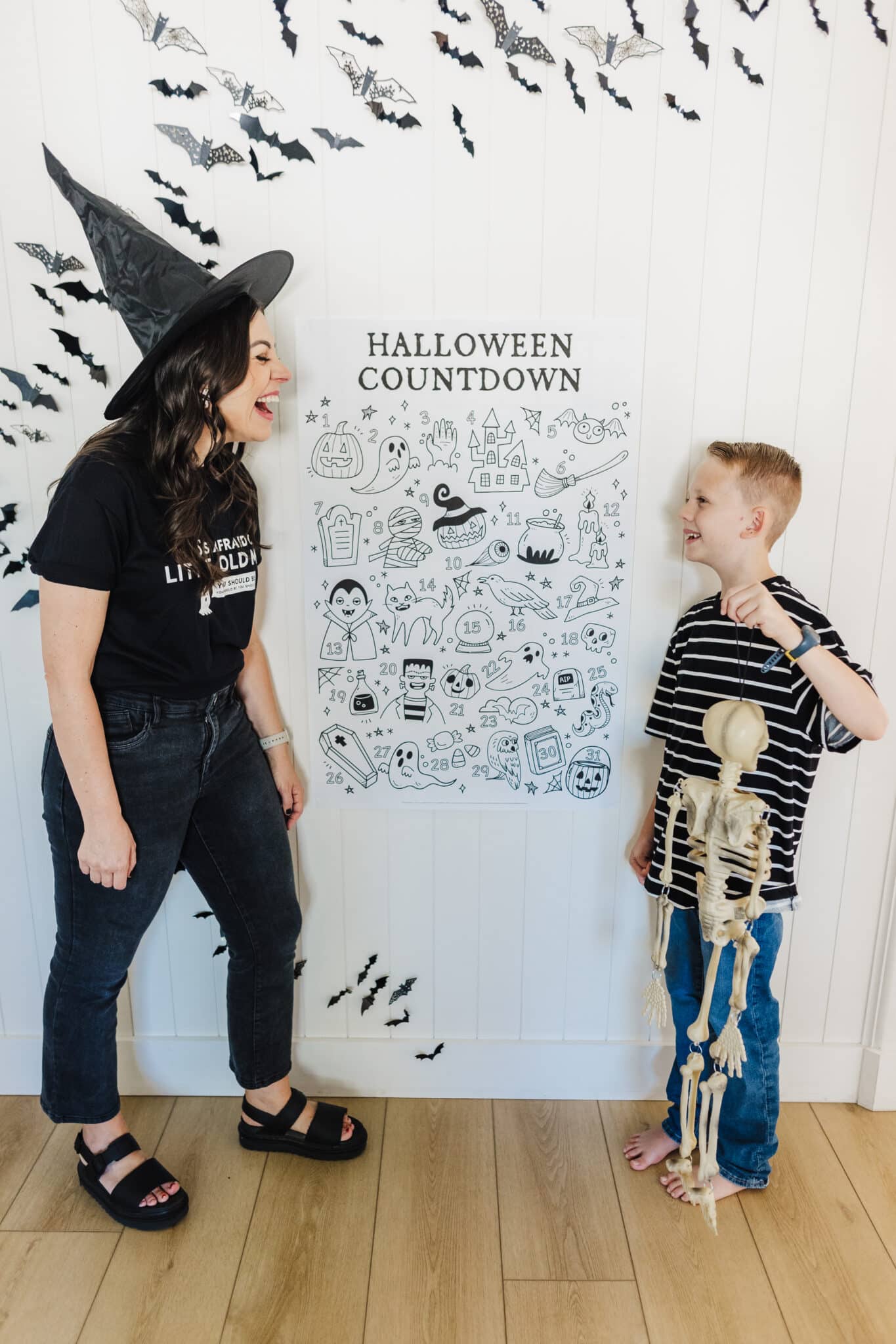 Halloween countdown calendar used as a Halloween advent calendar printed as an engineer print hung on a wall with a mom and son ready to use the free Halloween printable. 