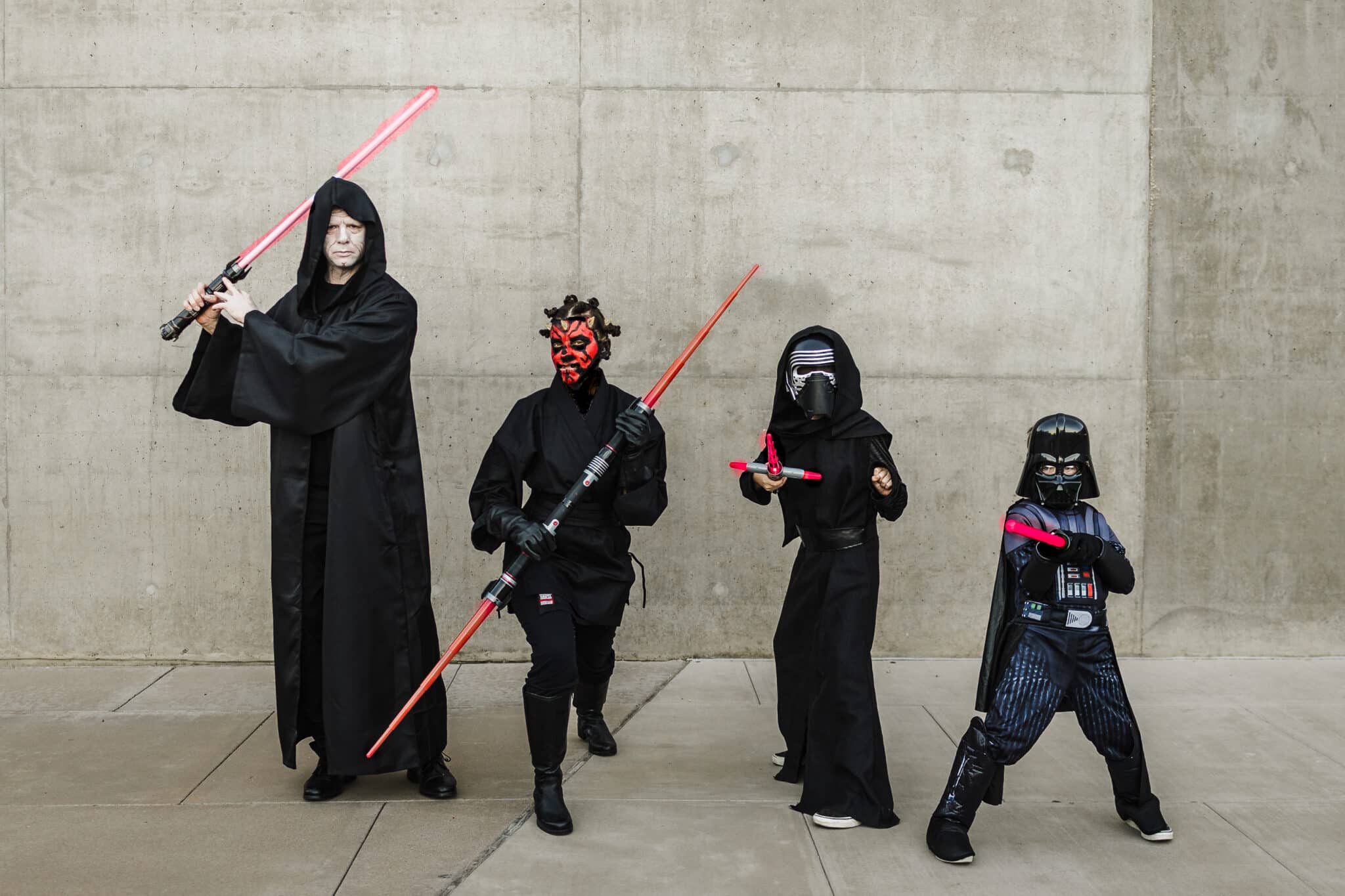 Star wars costumes showing the Dark Side with Star Wars Villains standing in a row holding red lightsabers.