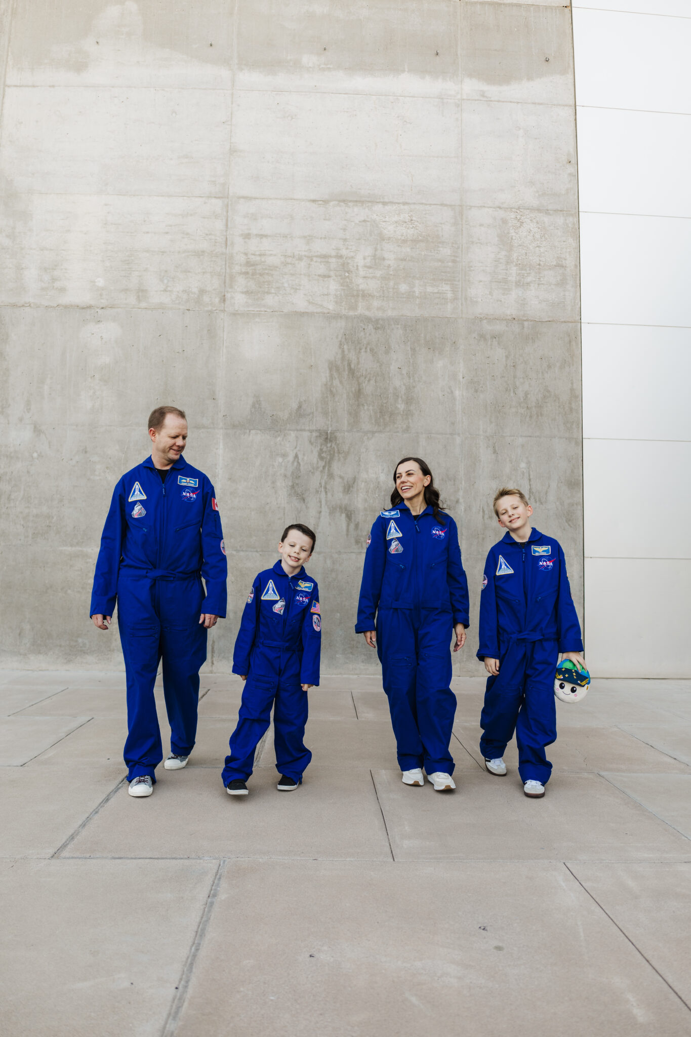 Artemis II space crew astronaut costumes with a family dressed as Jeremy Hansen, Victor Glover, Christina Koch, and Reid Wiseman holding RISE.